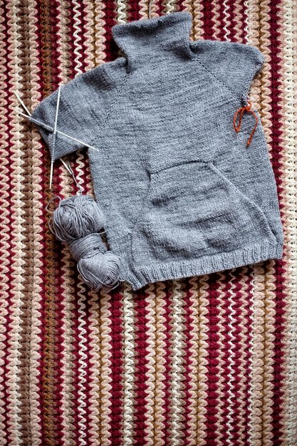 Camisola cinza de tricô incompleta para criança com agulhas