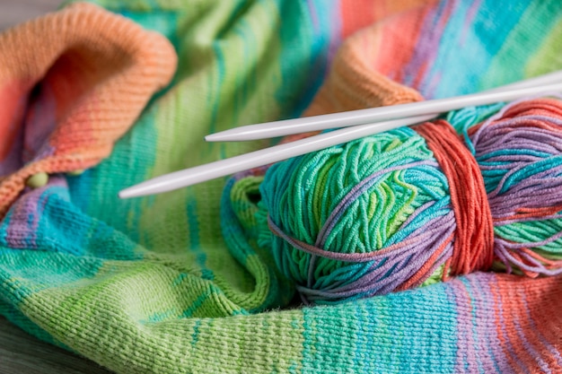 Camisola de malha, novelo Multicolor com agulhas perto dos produtos artesanais.