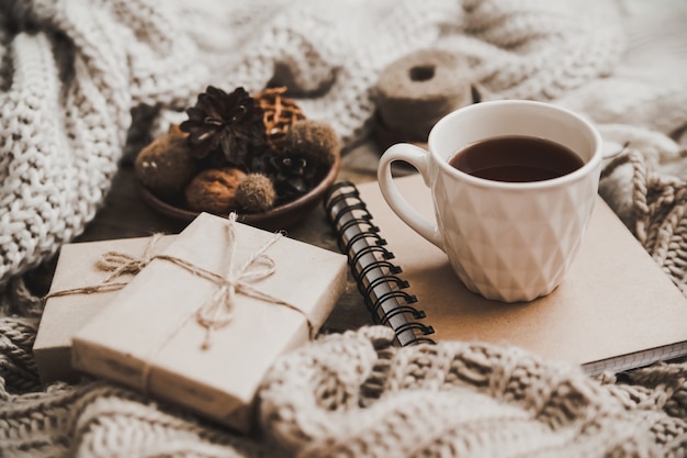 Camisolas e xícara de chá com caderno, vela e roupas de tricô