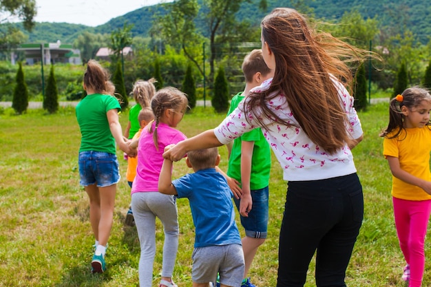 Campamento de arte al aire libre, hierba verde y día soleado. Tutor con niños juega y diviértete.