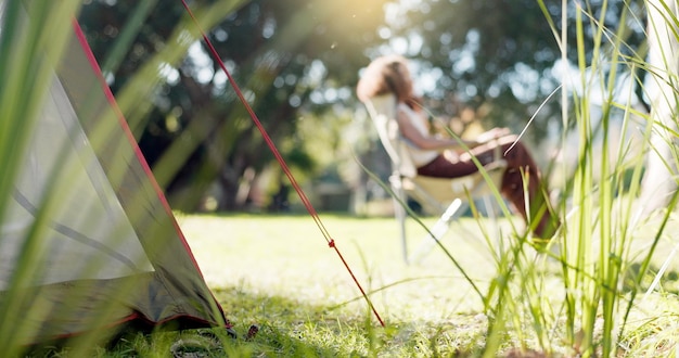 Foto campamento de la naturaleza y mujer sentada en un parque o bosque por la mañana para relajarse con aire fresco paz tranquila y persona femenina con silla en un jardín verde al aire libre en un viaje de fin de semana o aventura