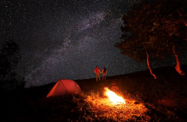 Foto campamento nocturno con fogata bajo un cielo estrellado brillante con una vía láctea brillante