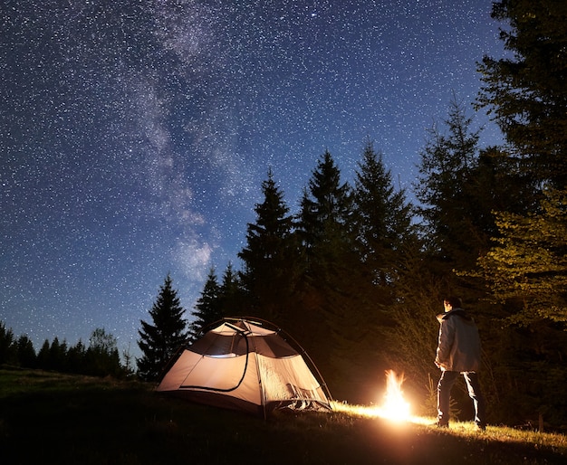 Campamento nocturno en las montañas bajo el cielo estrellado y la vía Láctea.