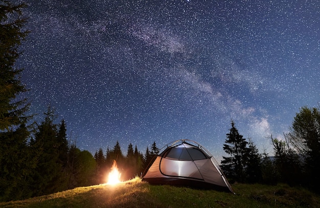 Campamento nocturno en las montañas bajo el cielo estrellado y la vía Láctea.