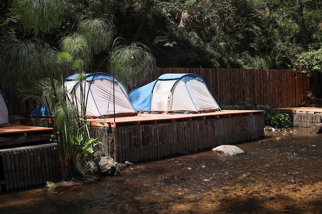 Un campamento con tiendas de campaña modernas en el bosque junto al río