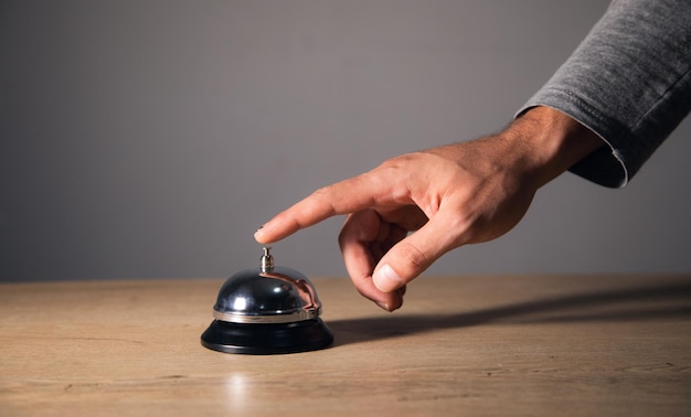 Campana de anillo de mano masculina en el mostrador de recepción del hotel