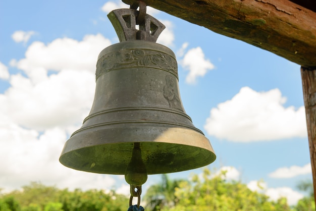 Campana de cobre colgando con cielo azul y nubes