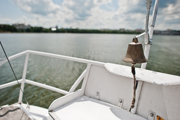 Campana de hierro en un pequeño yate en el lago.