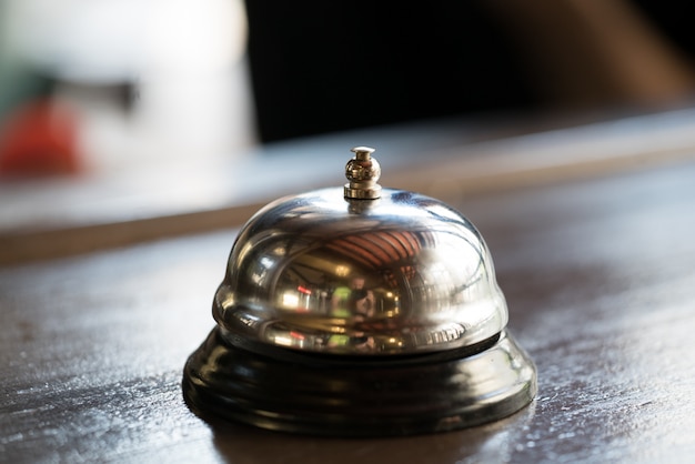 Campana para llamar a un camarero de un color dorado se encuentra en la mesa de madera en el restaurante.