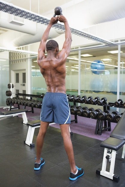 Campana sin mangas de elevación de la caldera del hombre muscular en gimnasio