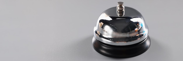 La campana plateada se encuentra sobre una superficie gris para llamar la atención, presione la campana para llamar al servicio