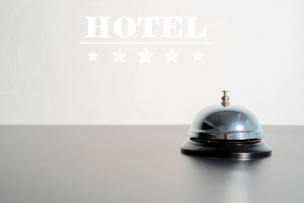 Campana de servicio de hotel en una mesa de vidrio negro y cartel de hotel y fondo de estrellas