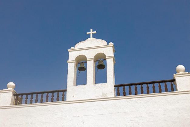 Campanario blanco de una iglesia sobre el cielo azul