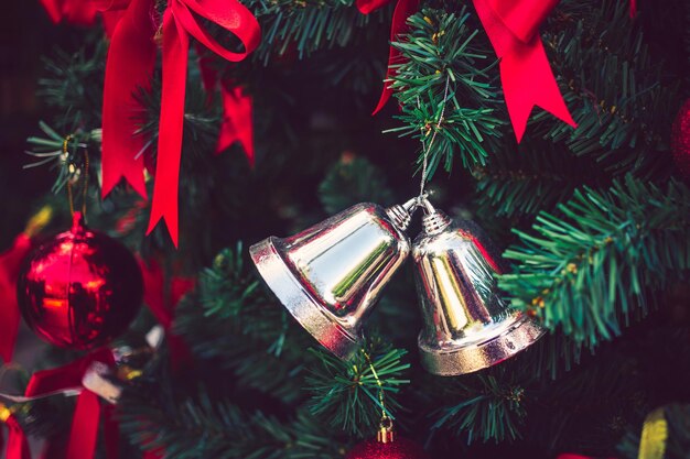 Campanas de plata gemelas y cinta roja con bolas rojas de Navidad adornan el árbol de Navidad Navidad