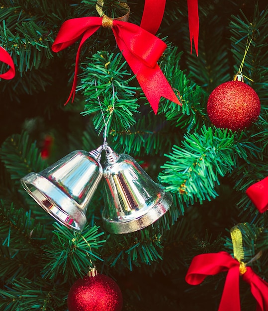 Campanas de plata gemelas y cinta roja con bolas rojas de Navidad adornan el árbol de Navidad