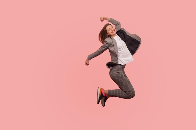 Foto campeón i39m retrato de mujer de negocios feliz extática entusiasta en traje elegante saltando despreocupado en el aire volando inspirado por el éxito celebrando el logro de la meta tiro de estudio interior aislado