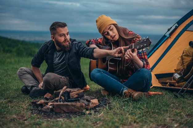 Camper, die beim Zelten in der Natur Gitarre spielen