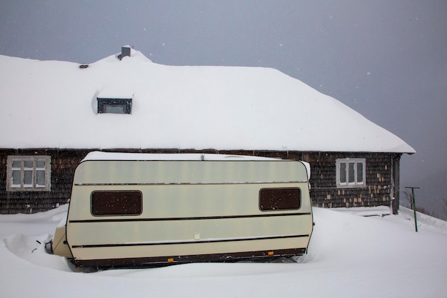 Camper uma pequena van para os amantes de viagens para a natureza perto da velha cabana coberta de neve