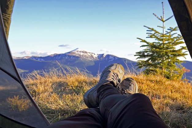 Camper de vacacionista de piernas en carpa con vista a la montaña