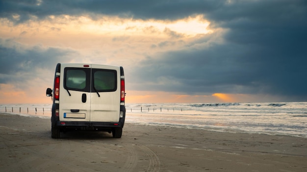 Foto camper van conduciendo junto al mar de wadden durante la marea baja, viajando en la playa de romo en dinamarca