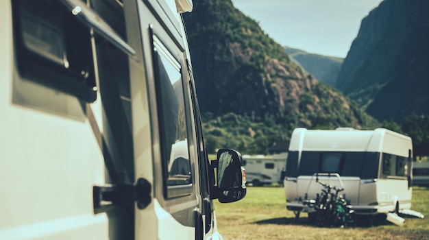 Foto camper van de veículo recreativo classe b e um trailer de viagem moderno em segundo plano dentro de um parque de trailers