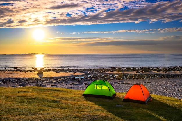 Camping al atardecer con tiendas de campaña en la playa de Uttakleiv en las islas Lofoten Noruega