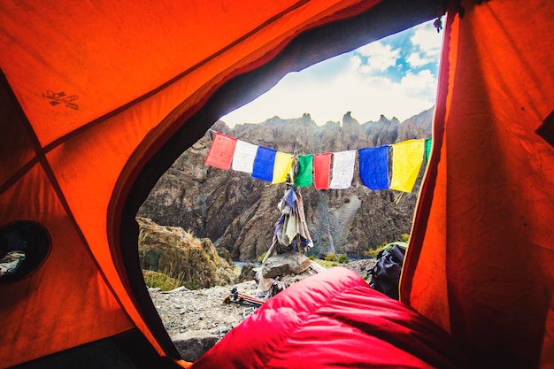 Camping im Himalaya-Gebirge, Blick vom Zelt am Morgen mit felsigen Bergen und Buddhisten