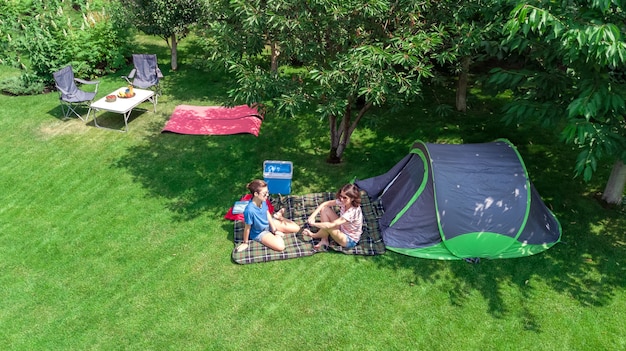 Camping-Luftbild von oben Mutter und Tochter, die Spaßzelt und Campingausrüstung unter Baumfamilienurlaub im Lager im Freienkonzept haben