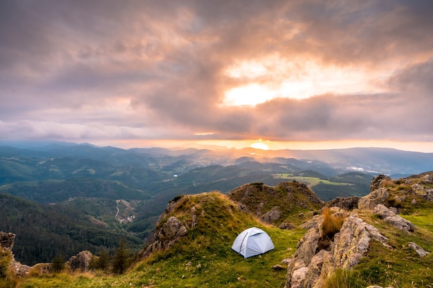 Camping salvaje en la cima de una montaña al atardecer, durmiendo al aire libre después de la larga caminata en las montañas.