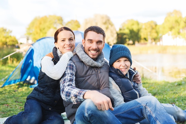 camping, turismo, senderismo y concepto de personas - familia feliz en una tienda de campaña en el camping