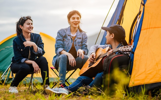 Camping, umgeben von einem Team asiatischer Kletterer, Wanderer, sie spielen zusammen Musik