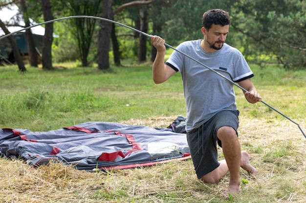 Camping, viajes, turismo, concepto de caminata - joven montando carpa al aire libre.