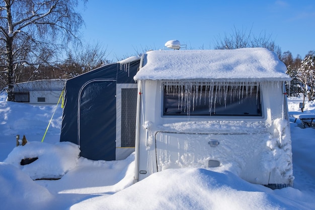 Foto campingplatz mit einem schneebedeckten und eisigen wohnwagen im winter