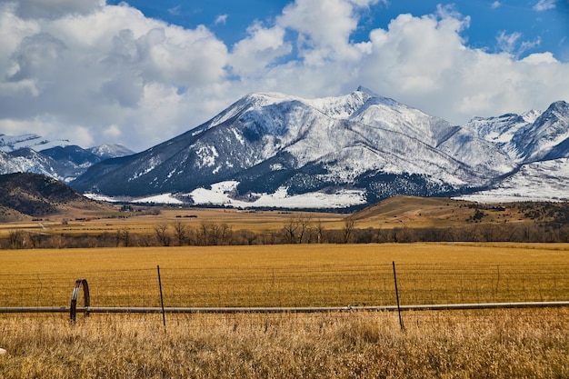 Campo agrícola e paisagem de cerca com impressionantes montanhas brancas de neve à distância