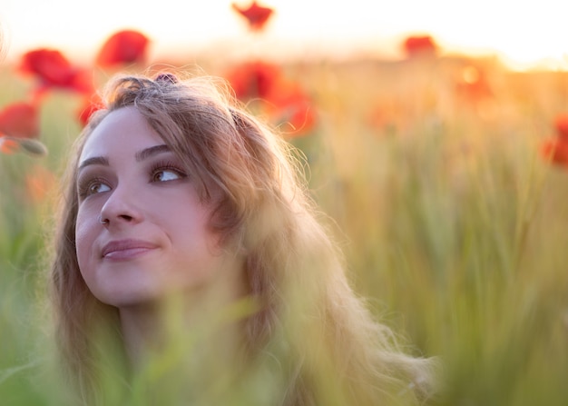 Foto campo de amapolas al atardecer mujer rubia