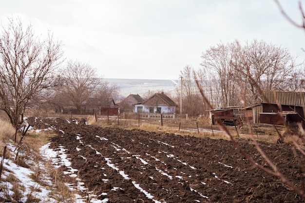 Foto campo arado con casas rústicas en el fondo