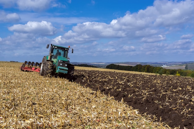 Un campo arado después de cosechar maíz con un tractor completo con un arado de ocho cuerpos.