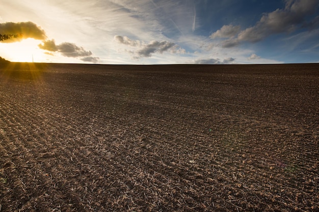 Foto campo arado preparado para plantar ao pôr do sol terras agrícolas e céu azul nublado