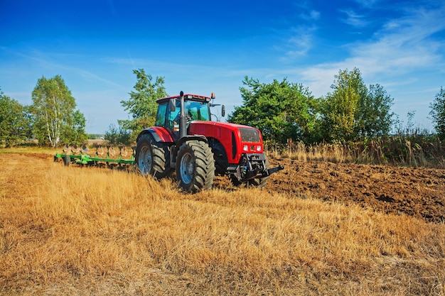 Campo de arado de tractor de procesamiento agrícola en concepto agrícola de primavera