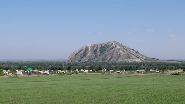 Campo de avena y pueblo al pie de Shihan Yuraktau República de Bashkortostán Rusia