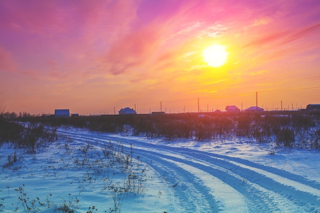 Campo y camino rural cubierto de nieve al atardecer