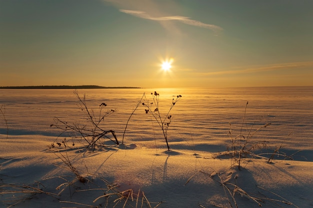 El campo cubierto de nieve en invierno. hora de la puesta del sol