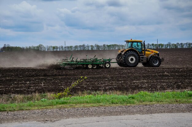 Campo de cultivo del tractor en un día nublado de primavera