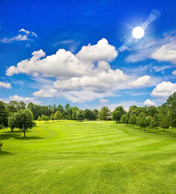 Foto campo de golfe e céu azul ensolarado. paisagem de campo verde europeu