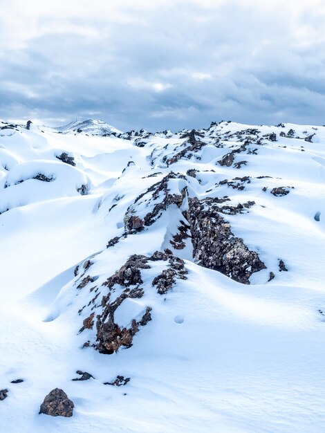 Campo de neve com montanhas brancas sob céu nublado na Islândia