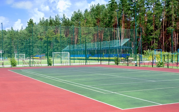 Campo esportivo na periferia da cidade em uma área arborizada. Vista da quadra de tênis, aparelhos de ginástica, campo de futebol e demais recintos públicos para jogos esportivos coletivos.