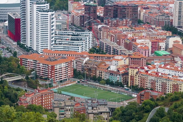 Un campo de fútbol está rodeado de edificios y un edificio blanco.