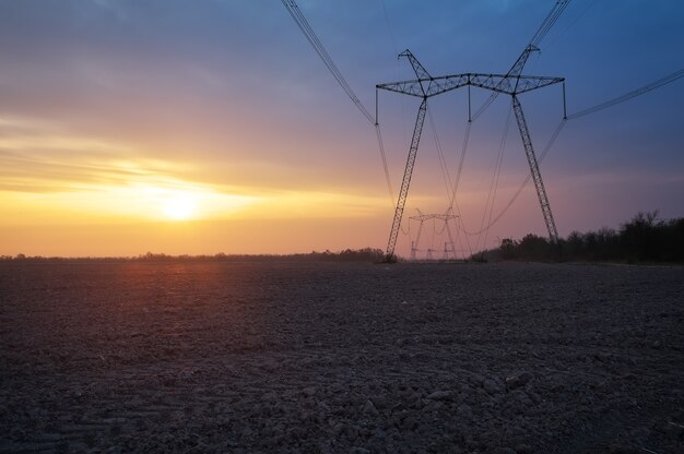 Campo y línea de energía eléctrica al amanecer.