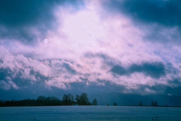 Campo nevado de invierno por la noche con cielo nublado