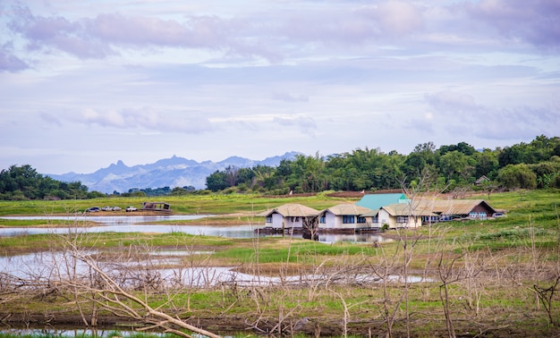 Campo perto do lago e montanha com céu nublado